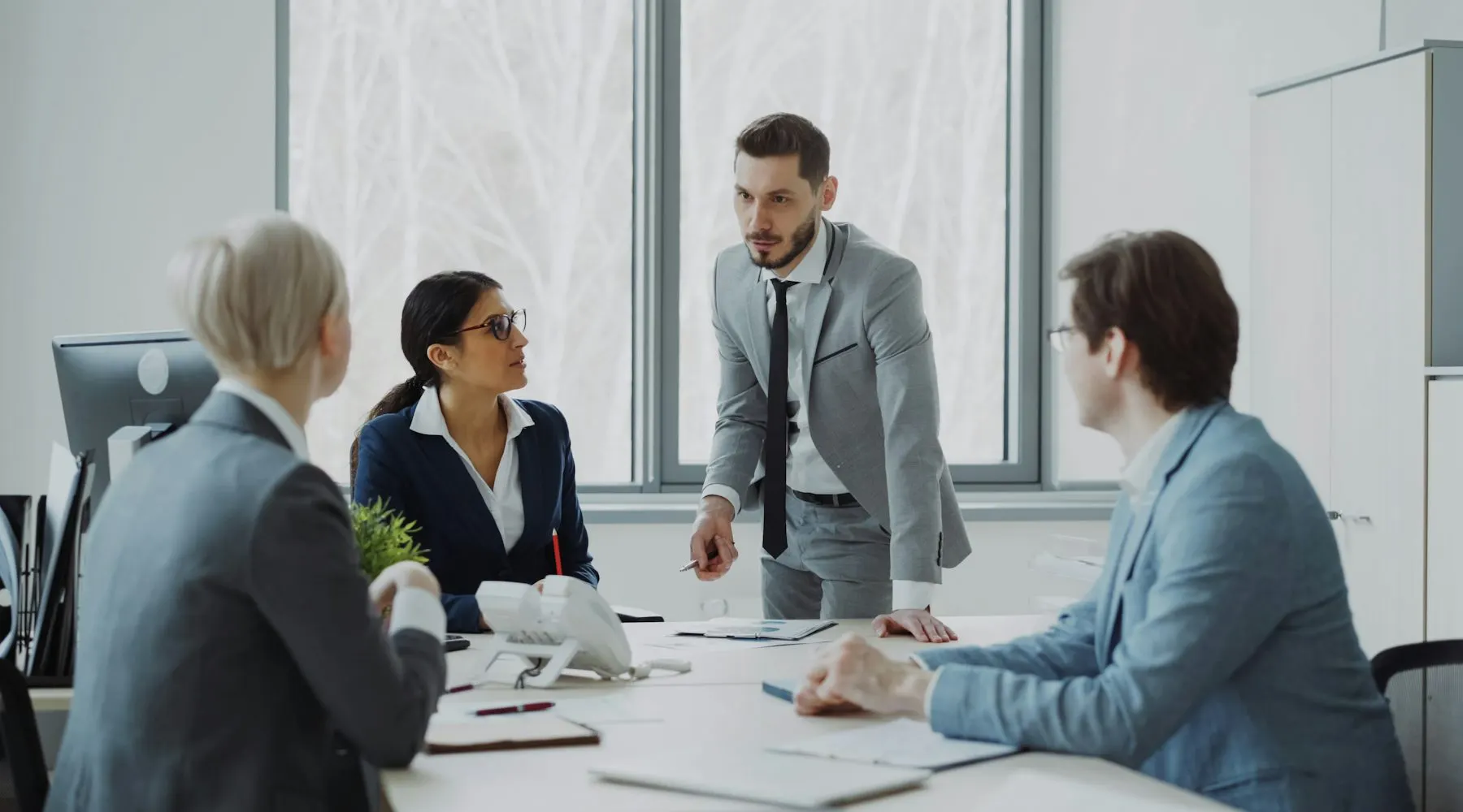 Consultant presenting to a seated client team in a bright meeting room
